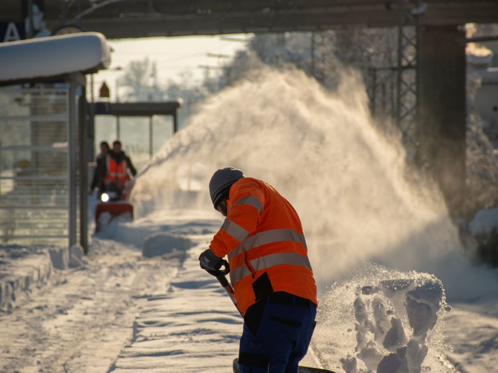 Mitarbeiter räumt im Winter den verschneiten Gehweg frei